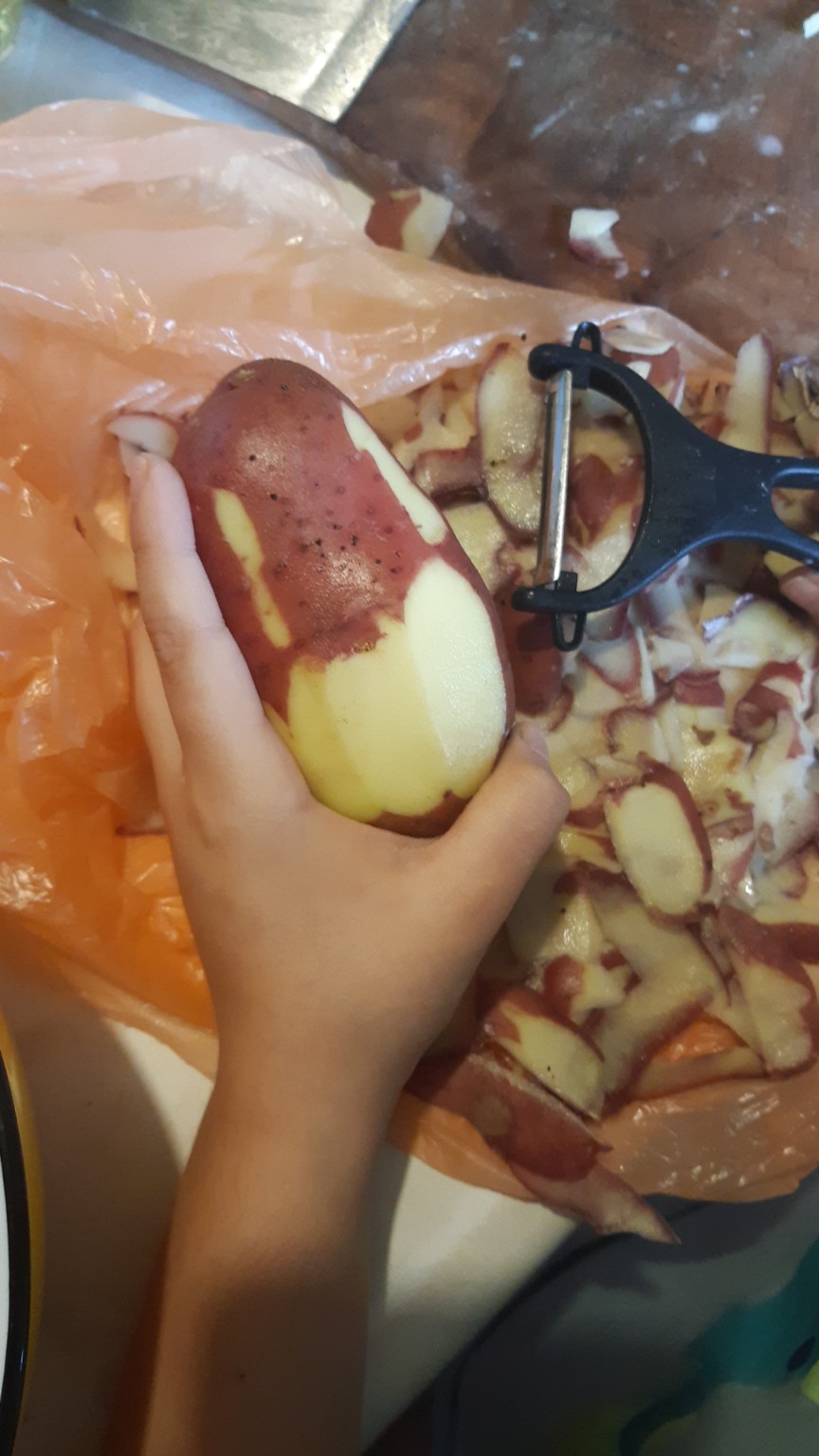 Manos de un niño pelando una papa a la que ha hecho una cara