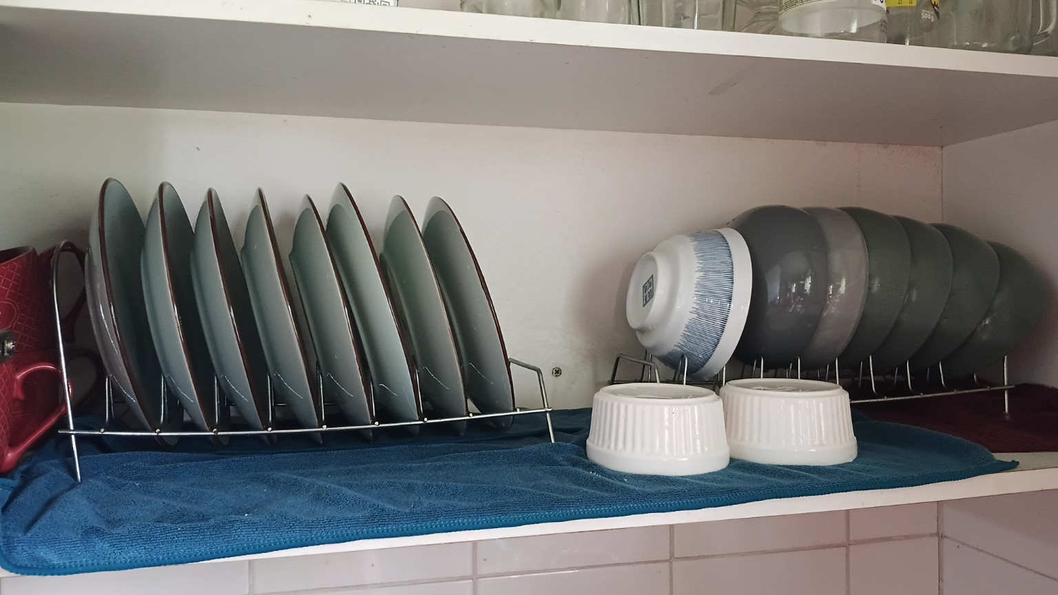 Platos y cuencos en organizadores metálicos sobre un paño dentro del mueble